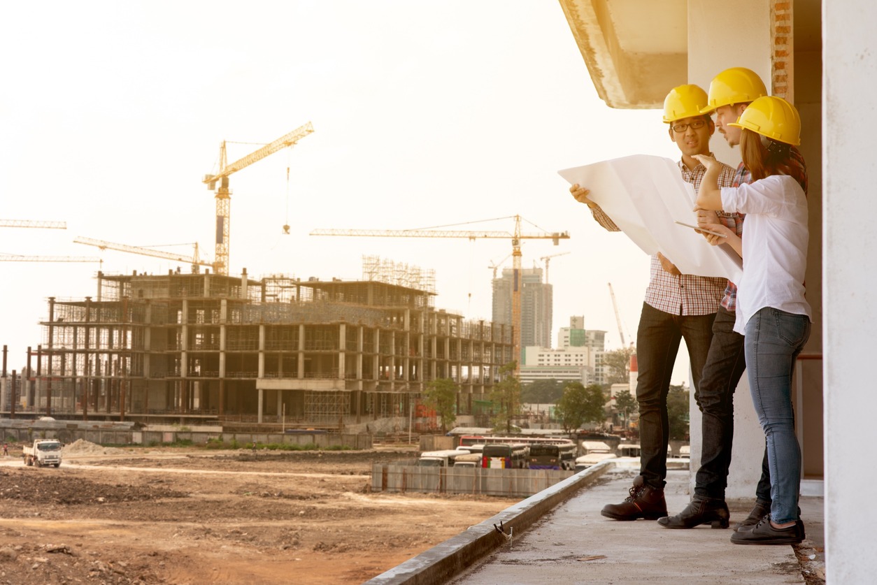 ingenieros consultan planos con obra de fondo